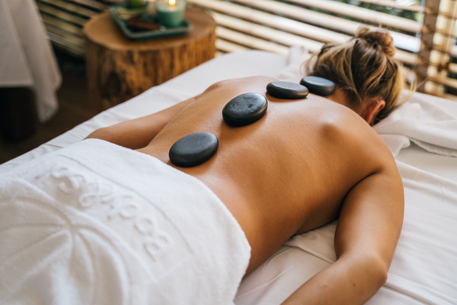 Cliente détendue sur la table de massage, pierres posées sur le dos